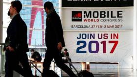 Asistentes al Mobile World Congress del año pasado, arrastrando maletas ante un cartel de la feria / EFE
