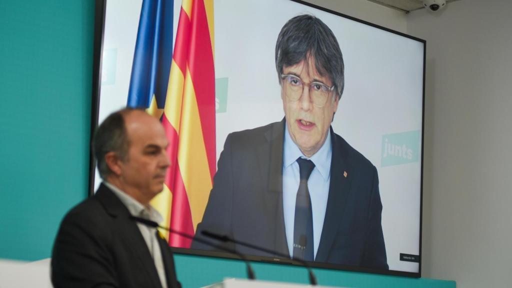 En la pantalla, Carles Puigdemont, presidente de Junts, y en primer plano su secretario general, Jordi Turull (imagen de archivo)