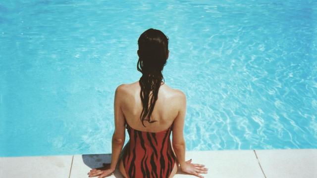 Mujer disfruta sentada junto a una piscina